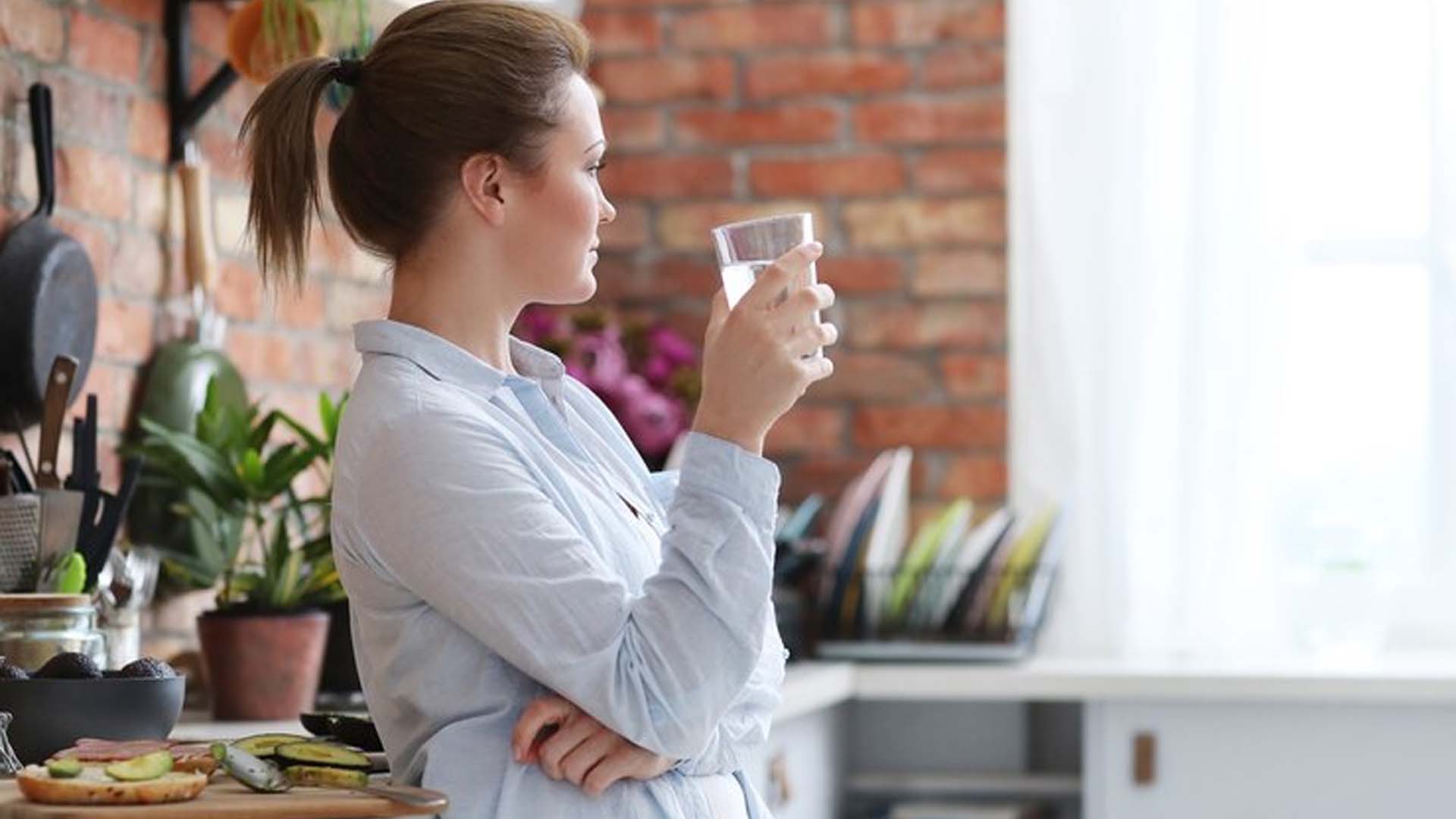 Women in kitchen Drinking warm or hot water