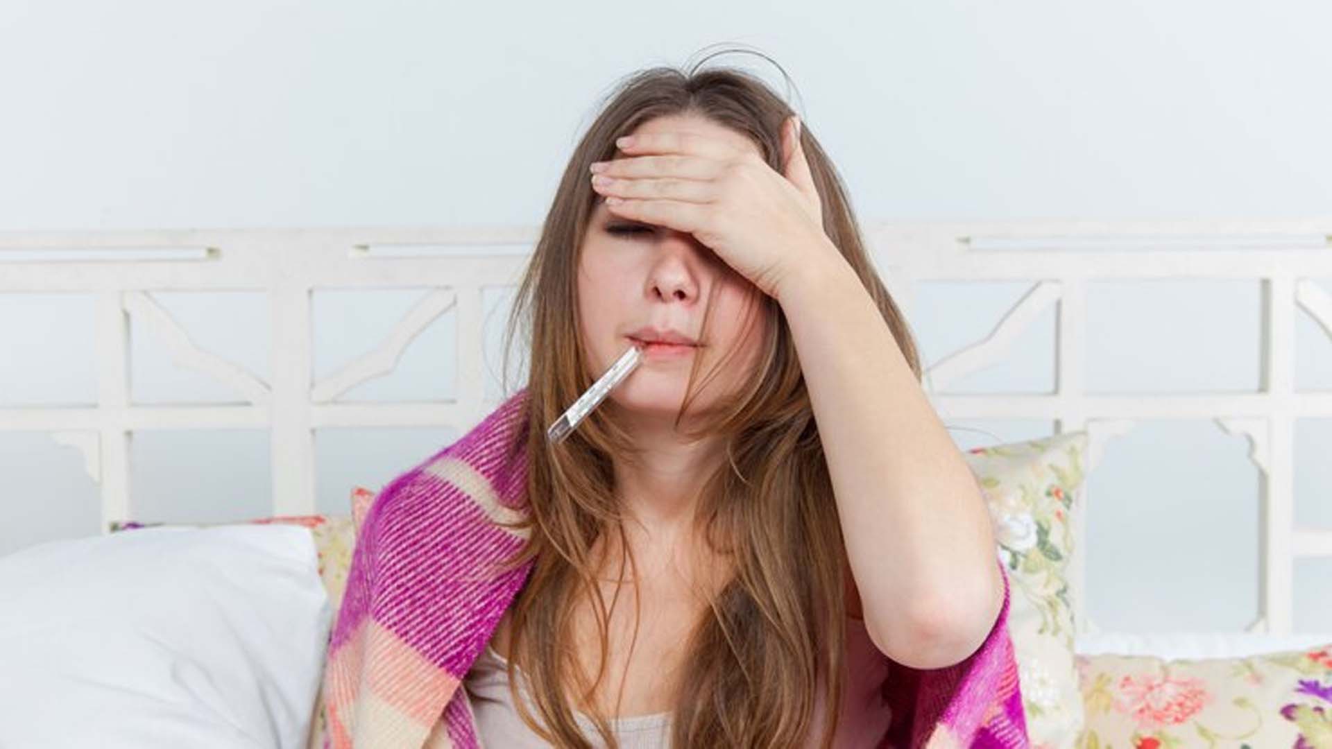 Women with Fever holding thermometer