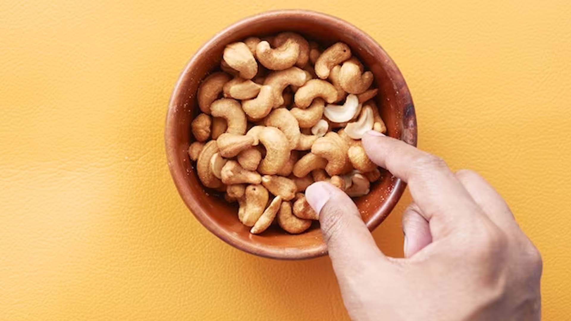 Person picking cashew from bowl