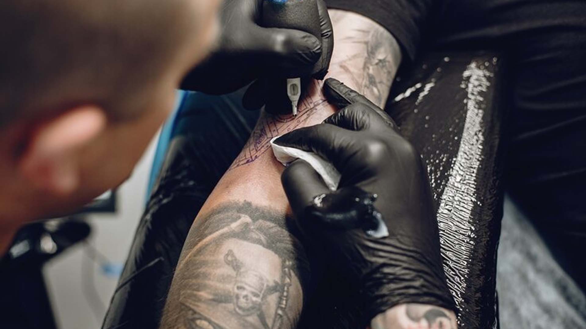 Man tattoos on his skin in tattoo studio